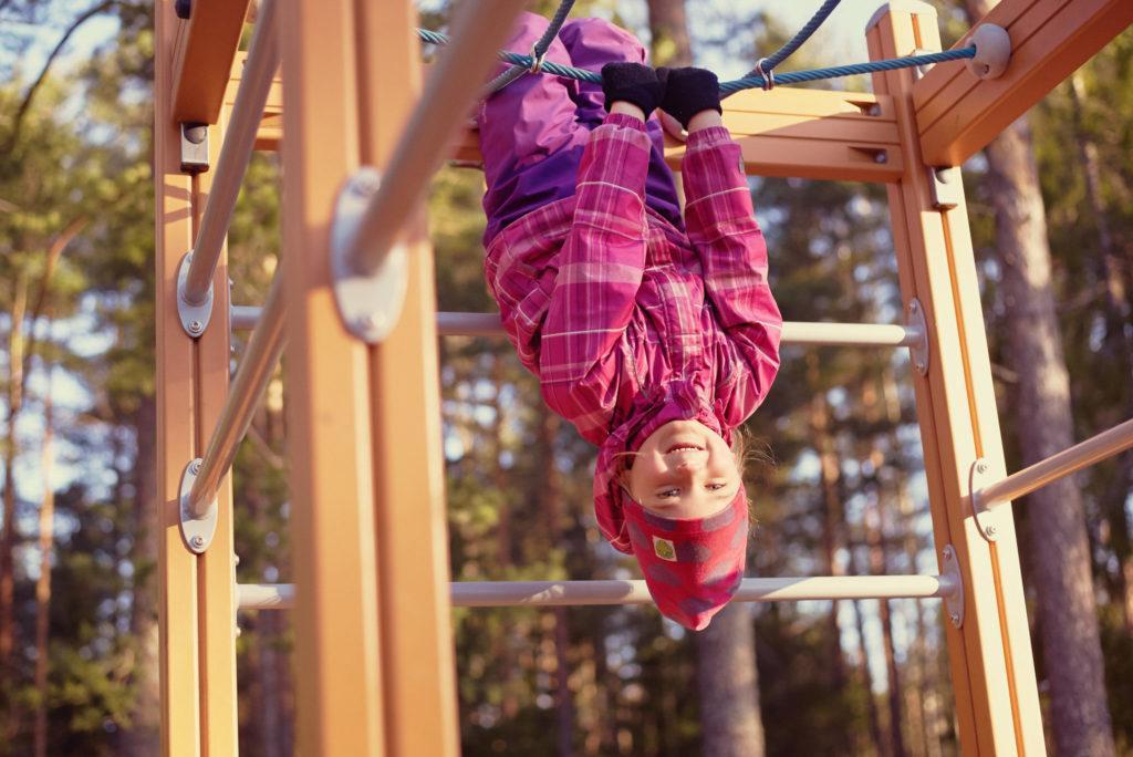 A child hanging upside down in a playground.