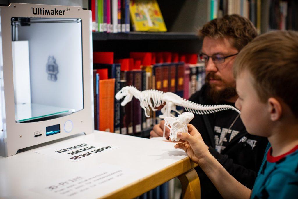 Kirjaston työntekijä ja poika ovat tulostaneet 3D-tulostimella dinosauruksen.