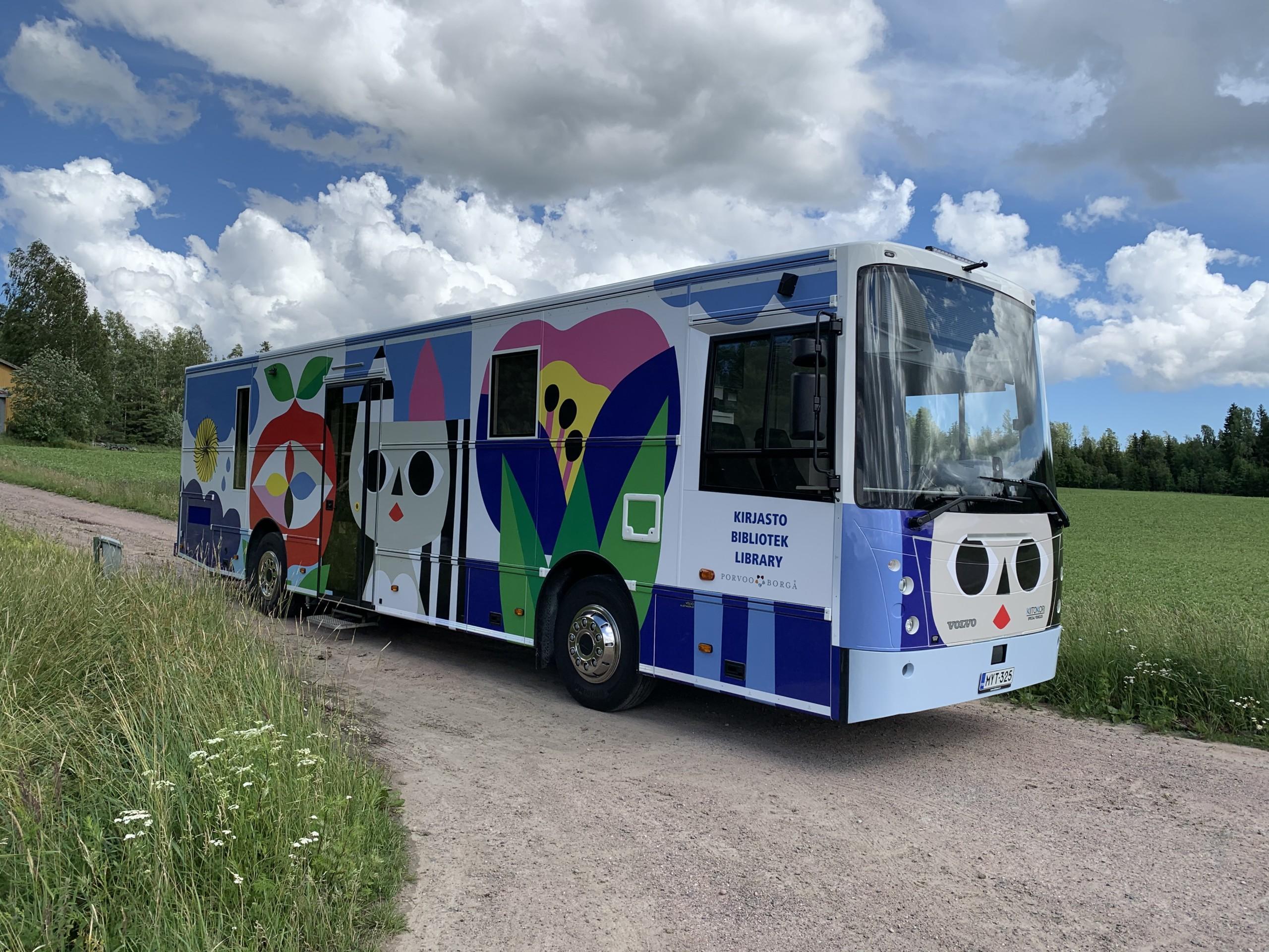 Bokbussen kör på sandväg i lummigt landskap.