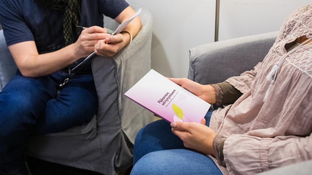 två personer sitter med papper i sina händer