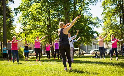 En kvinna leder parkgymnastik för en grupp människor.