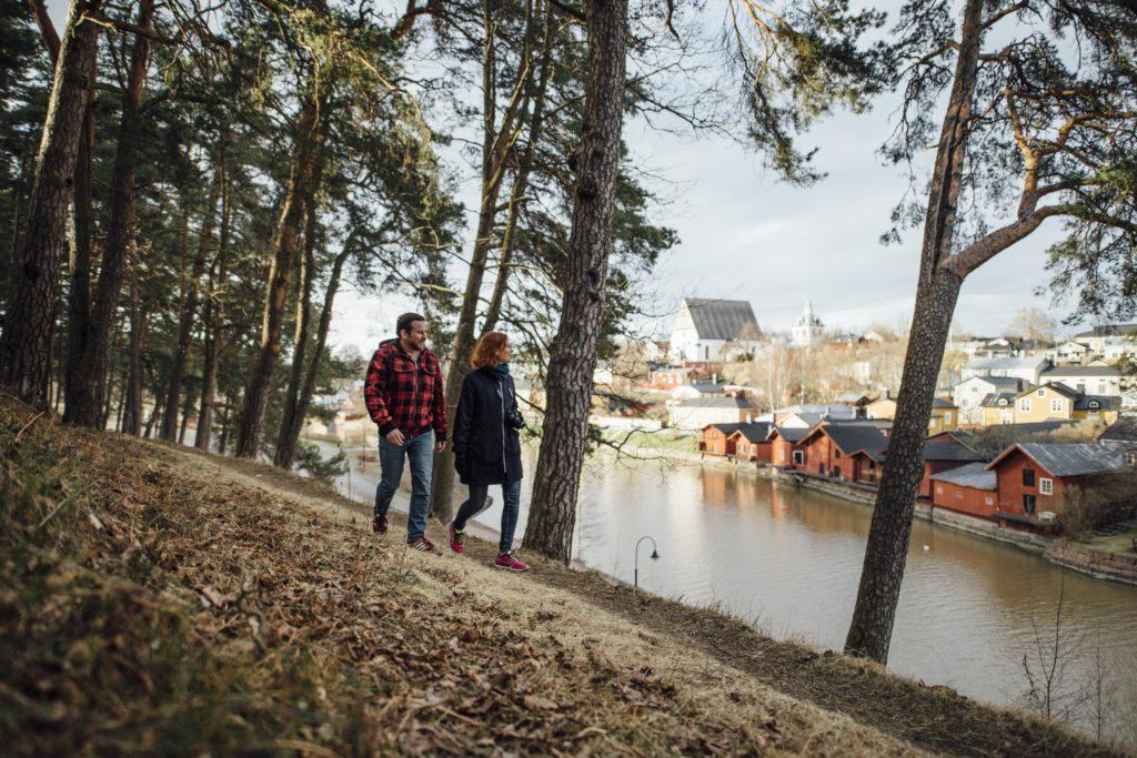 Ett par promenerar på Näsebacken och strandbodarna kan ses i bakgrunden.