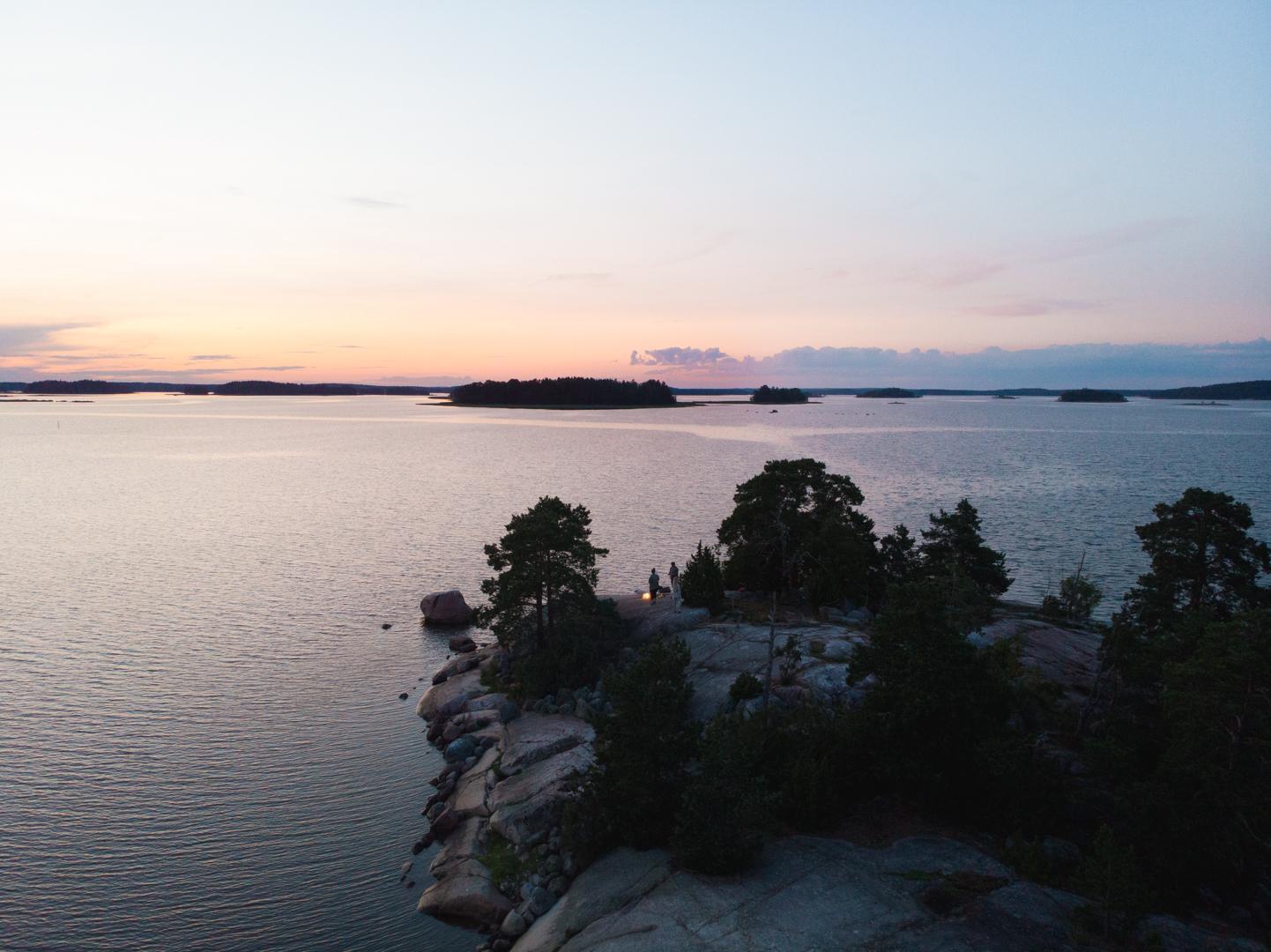 Meri, kallio ja saaria auringonlaskussa.