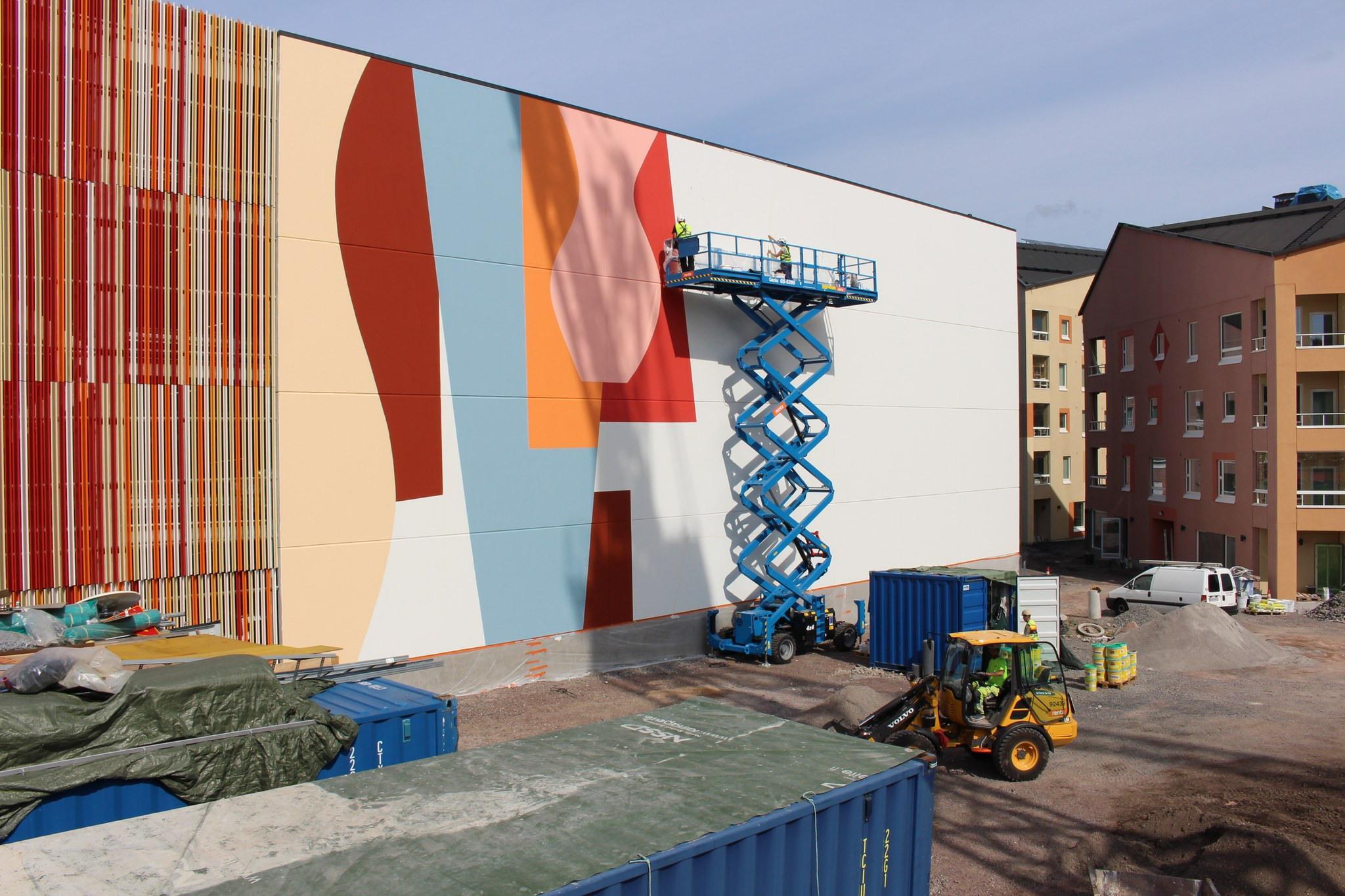 Taideteosta maalataan rakennuksen seinään.