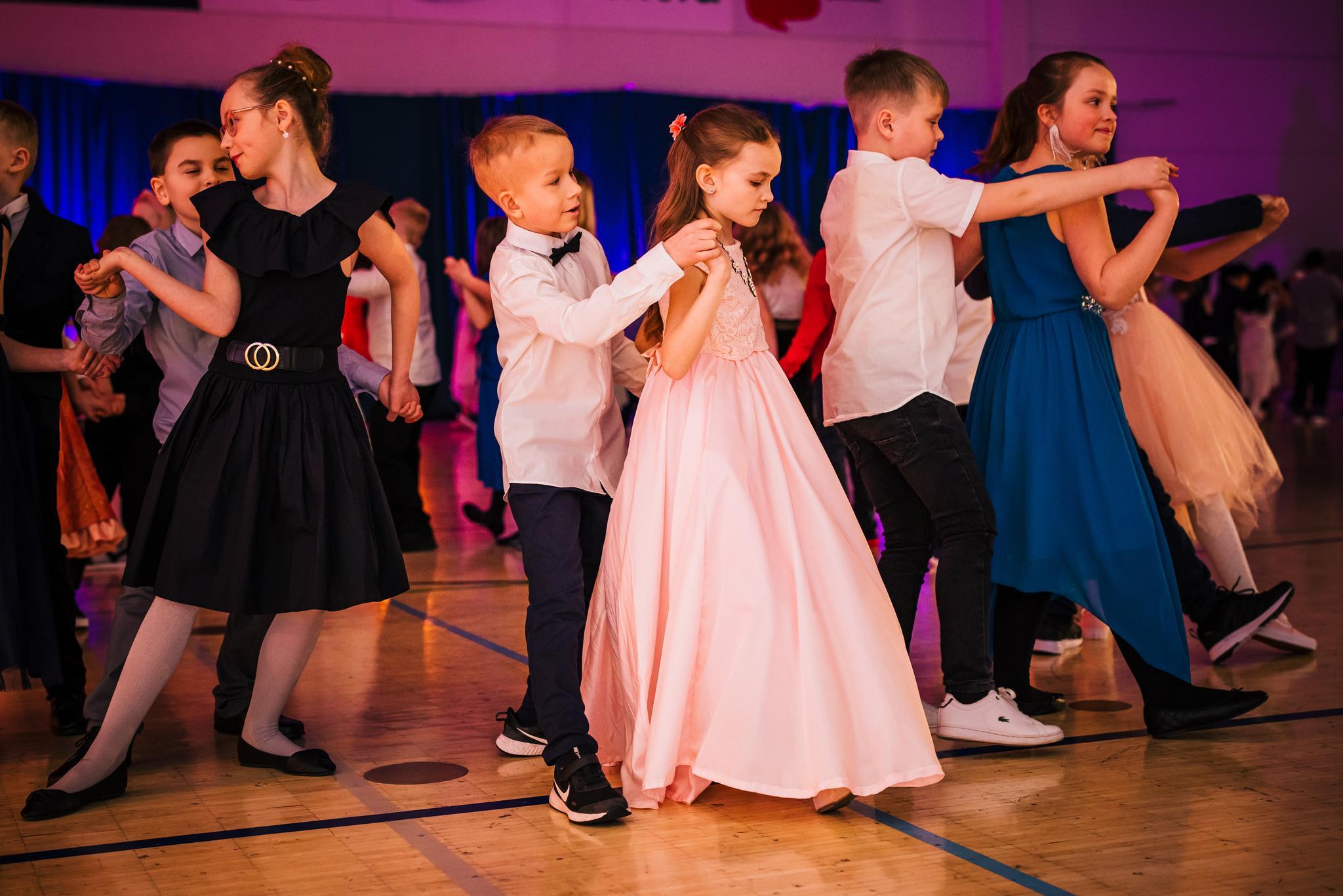 Juhlavaatteisiin pukeutuneet alakouluikäiset lapset tanssivat paritansseja