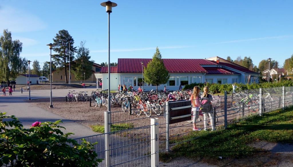 Lapsia ja polkupyöriä koulun pihalla.