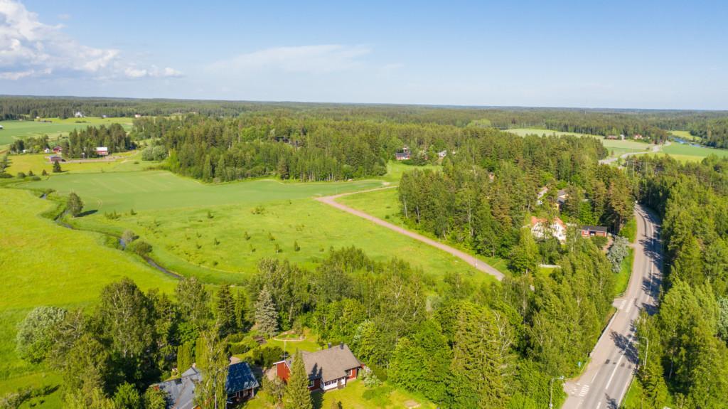 Flygbild över Carlandersvägens småhusområde före det finns hus på området samt omgivande landskap.