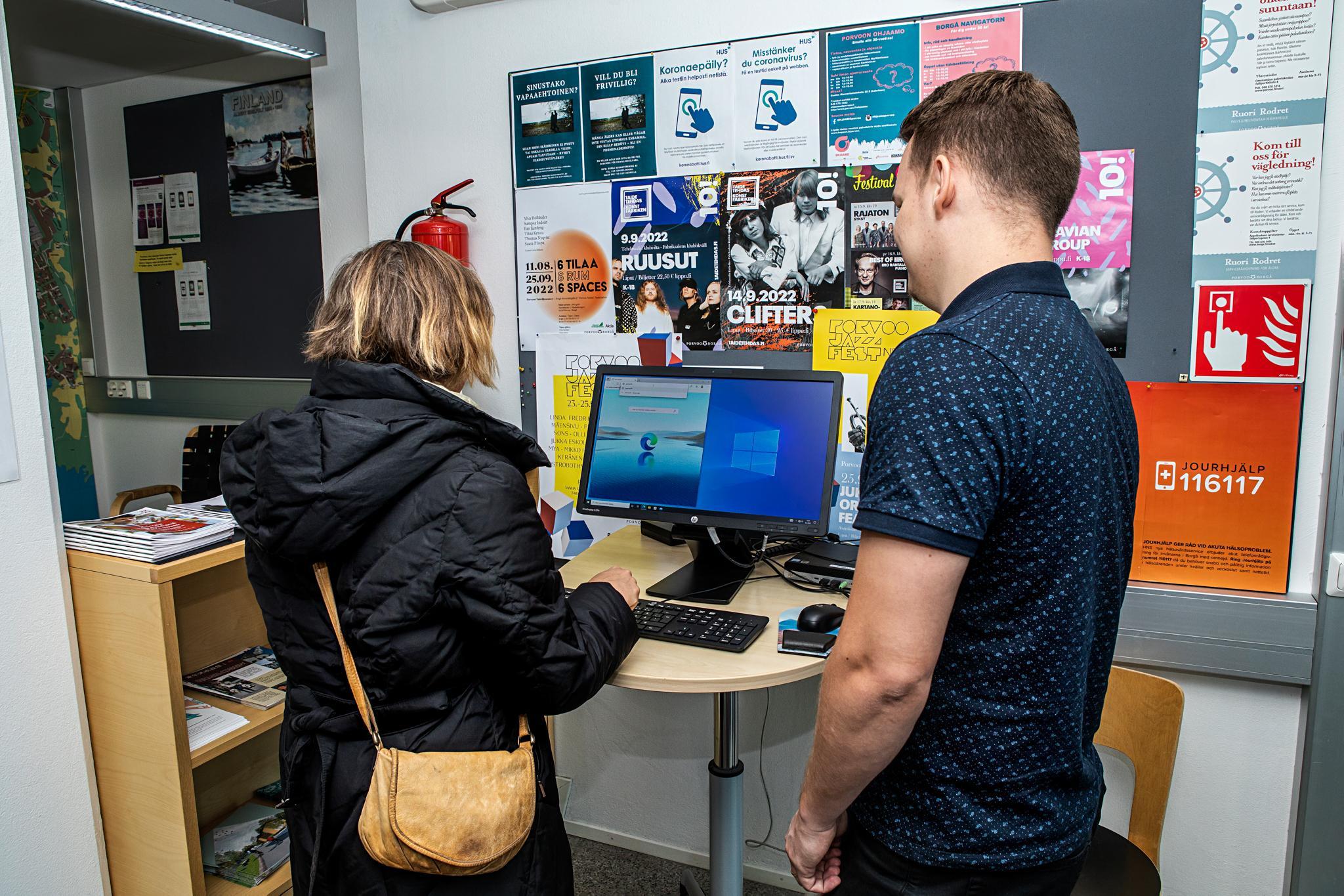 Palvelupiste Kompassin asiakasneuvoja auttaa asiakasta tietokoneen käytössä.