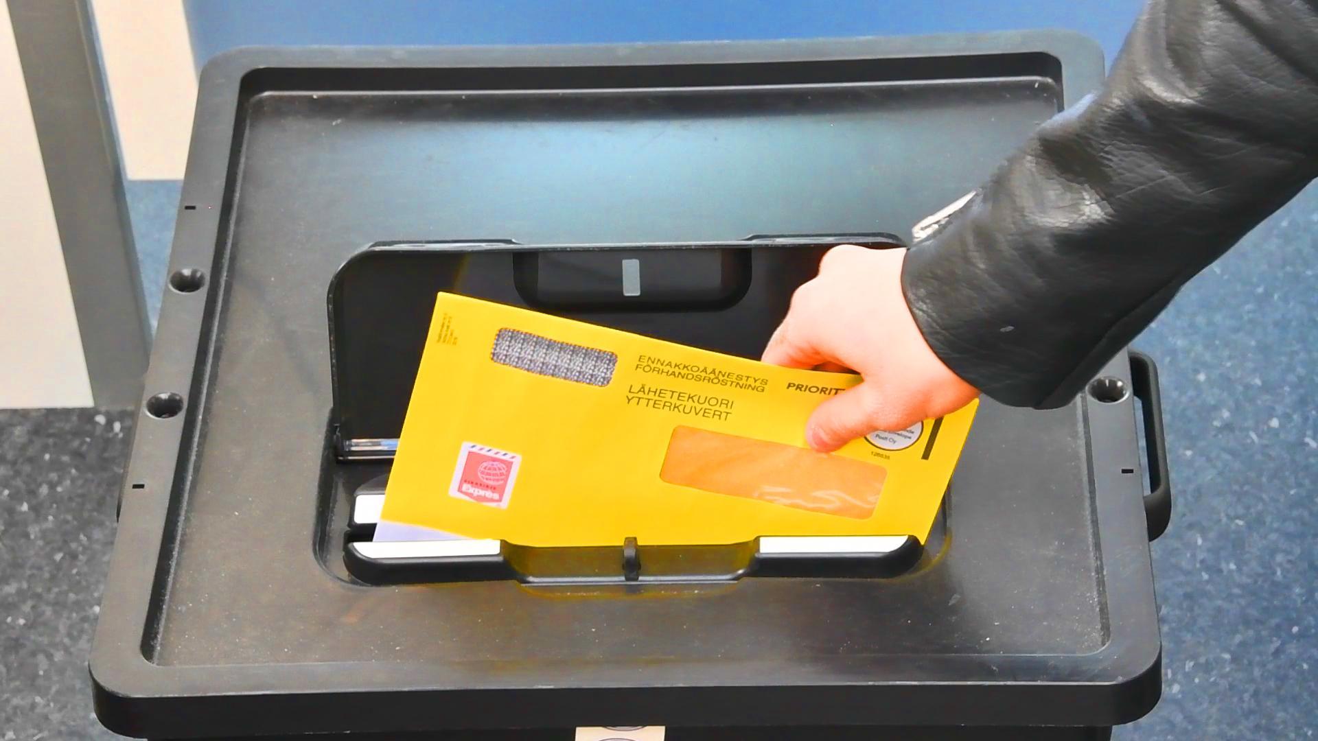 En person lägger röstningskuvertet i valurnan.