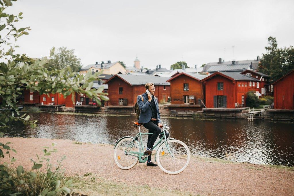 Pyöräilijä Porvoon jokirannassa. Taustalla ranta-aitat.