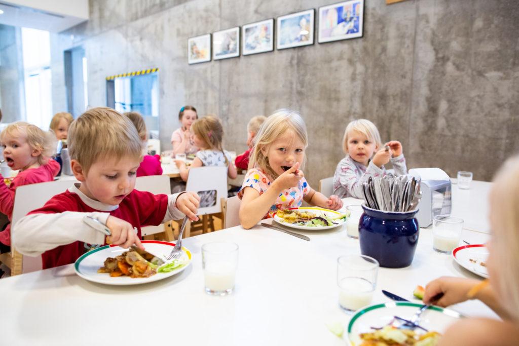 Barn äter lunch i daghemmets matsal.