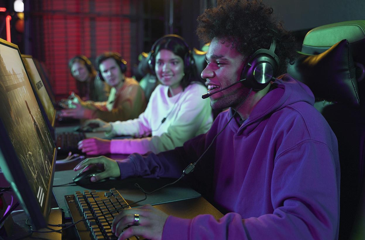 Nuoret pelaavat tietokoneilla. Kuva on otettu sivusuunnasta