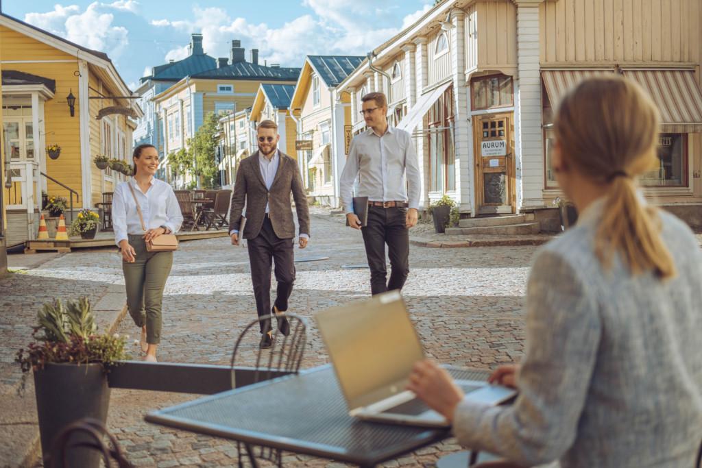 En kvinna sitter och jobbar vid sin dator i Gamla stan i Borgå och tittar på människor som går förbi.