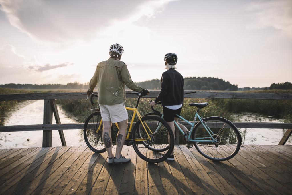 A photo of two cyclists stopped on a bridge admiring the view.