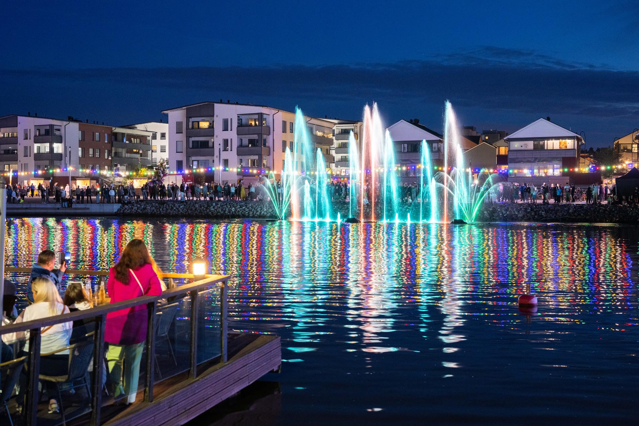 Dancing fountains show and colorful lights reflecting on the river.