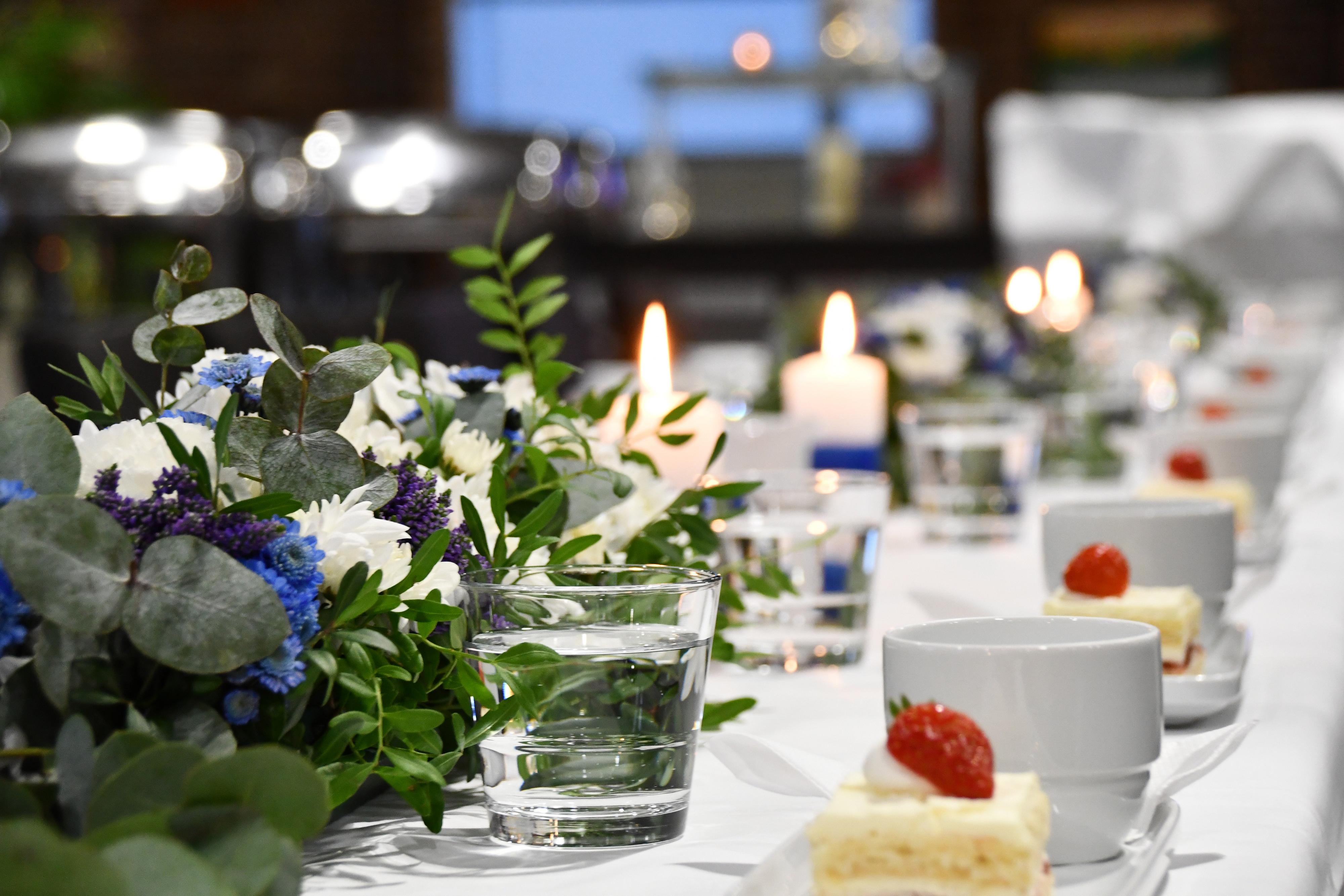 Festlig kaffebord dekorerad med blåvita ljus och blommor.