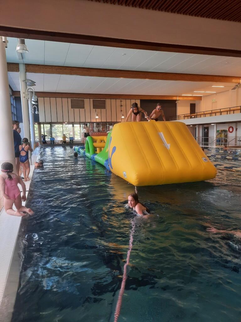 En rutschbana i poolen och barn som leker.
