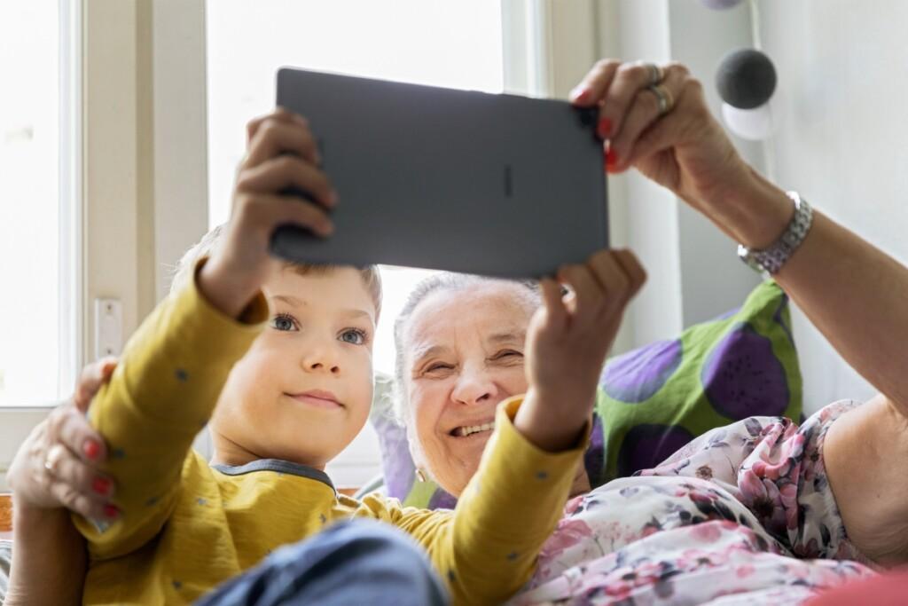 En farmor och en pojke läser med en tablett.