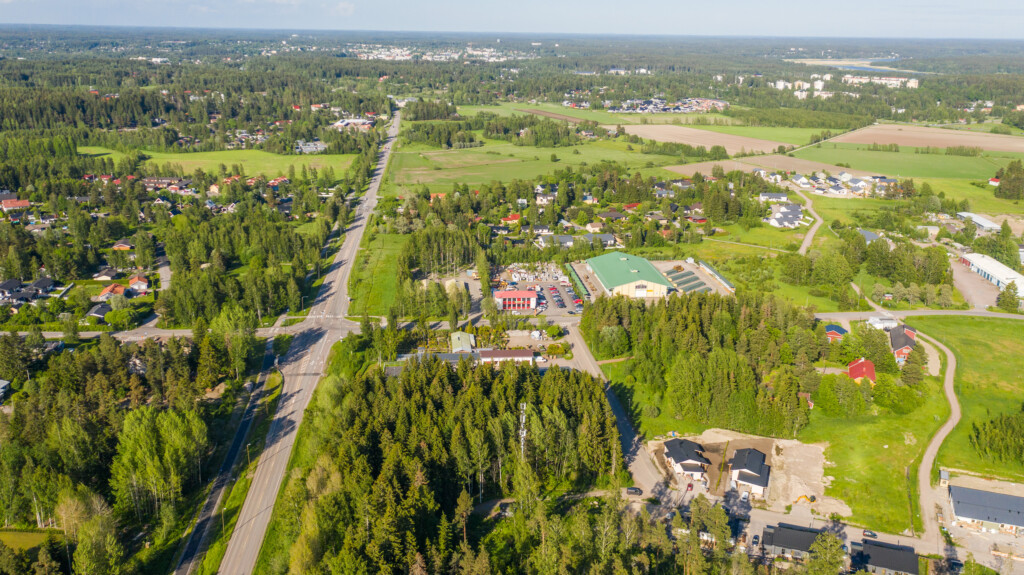 Ilmakuva Raivaajantie 10:n tonteista omakotivaltaisen asuinalueen laidalla. Lähellä näkyy yritystontteja, vähän kauempana on metsä- ja peltomaisemaa.