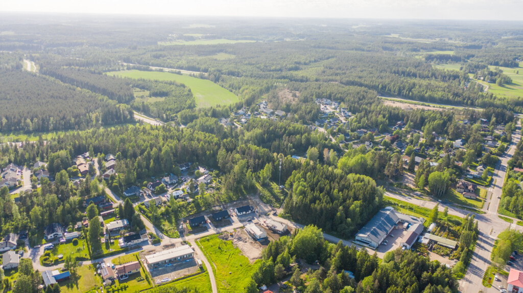 Ilmakuva Raivaajantie 10:n tonteista omakotivaltaisen asuinalueen laidalla. Lähellä näkyy yritystontteja, vähän kauempana on metsä- ja peltomaisemaa.