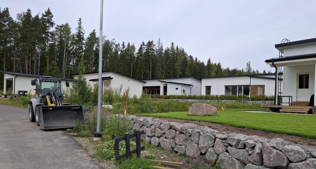 Valokuva rakentamattomasta tontista osoitteessa Annelintie 7 valmiiden omakotitalojen ympäröimänä.