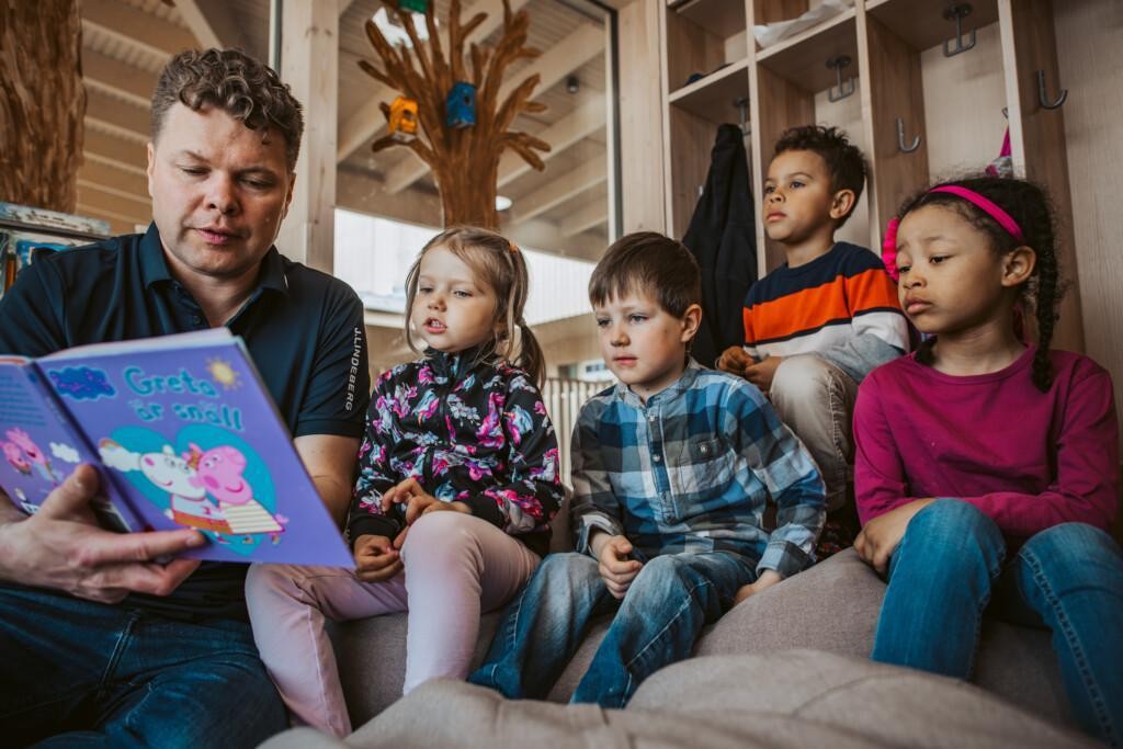 Päiväkodissa aikuinen lukee lapsille kirjaa.
