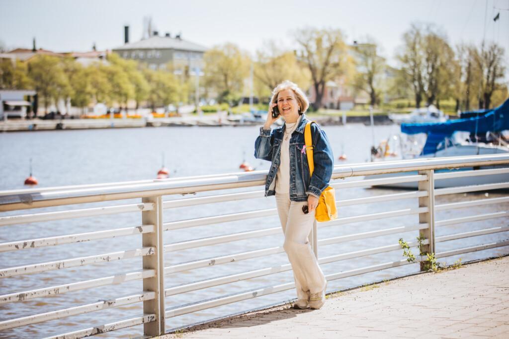 Nainen puhuu puhelimessa ulkona Porvoon jokirannassa.