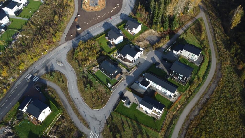 Flygfoto med egnahemshus och parhus. I slutet av Niittysyrjävägen finns en delvis grusbelagd tomt som gränsar till en liten parkskog.