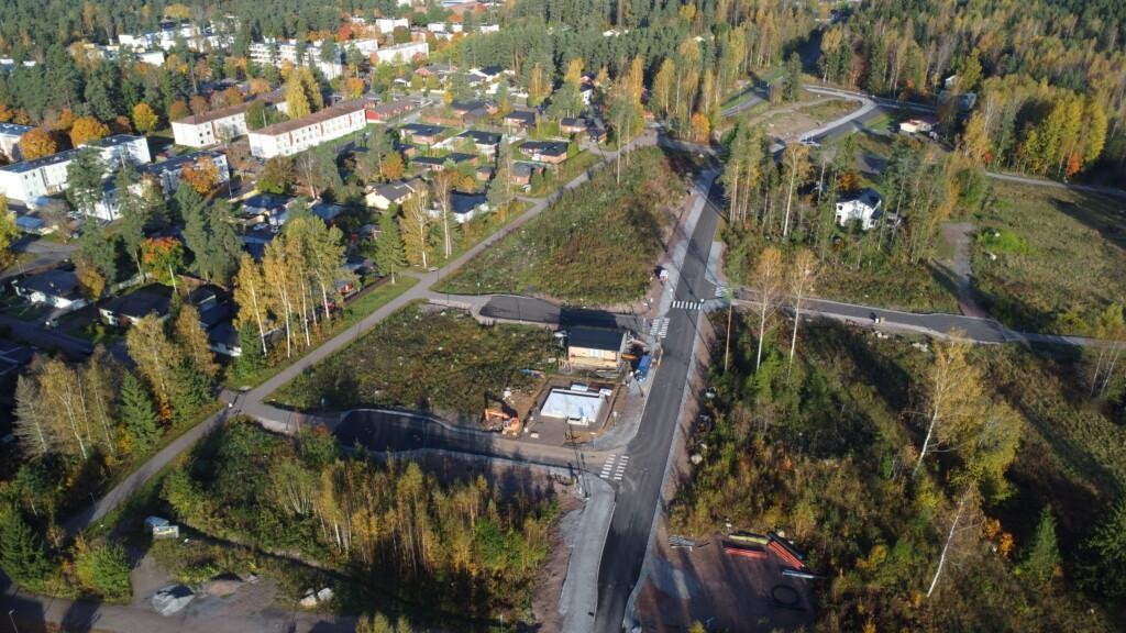 I mitten av flygfotot finns en ny gata med korsningar. Längs gatan finns ett egnahemshus under byggnad samt grunden till ett annat hus. Runt gatorna finns obebyggda tomter och några äldre egnahemshus. I bildens övre vänstra del syns befintlig småhus- och höghusbebyggelse, och i bakgrunden skog i höstens färger.