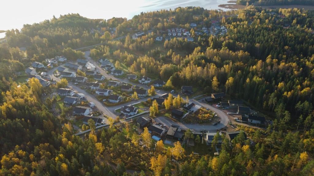 Ilmakuva, omakotitaloja ja muutama tyhjä tontti metsän ympäröimällä alueella. Kauempana lisää pientaloja ja rivitaloja sekä merta.