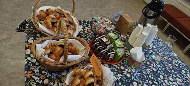 Pullia, pillimehuja, teepusseja, kertakäyttöastioita, servettejä, vesikannu ja termari pöydällä.