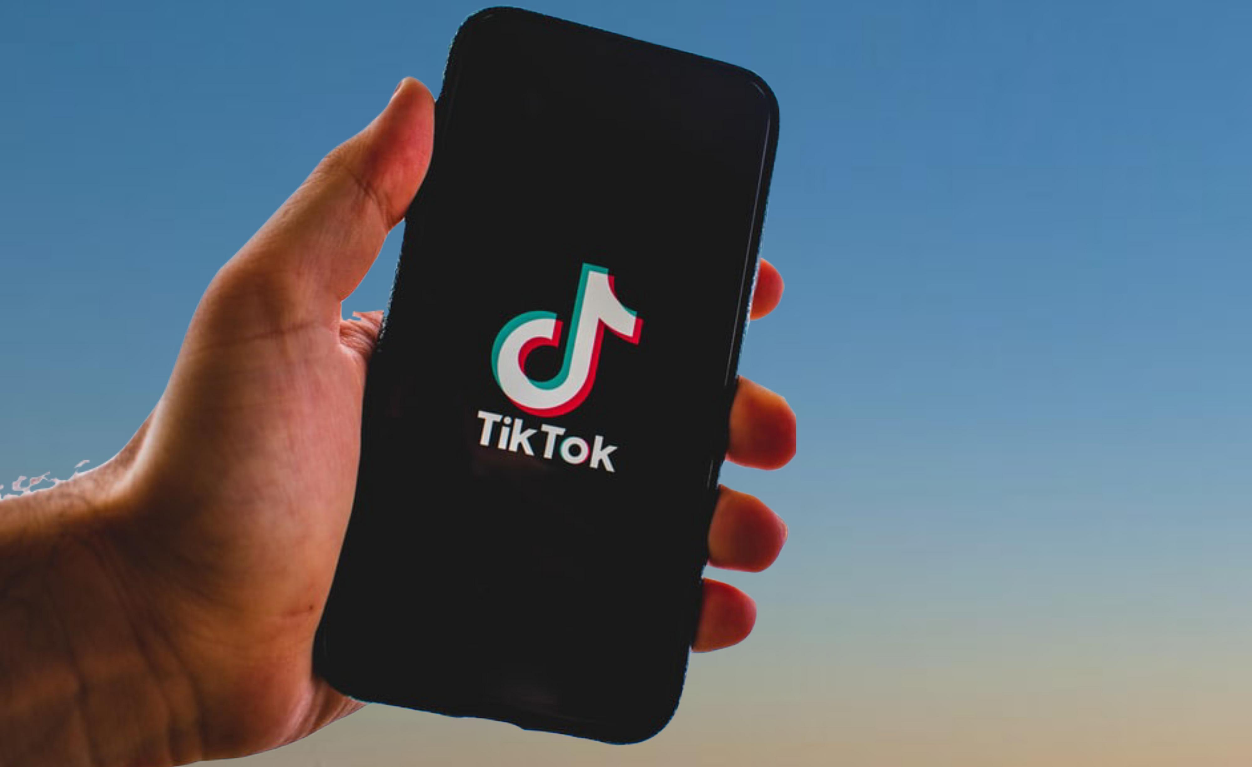 Käsi ja älypuhelin, jossa TikTokin logo.