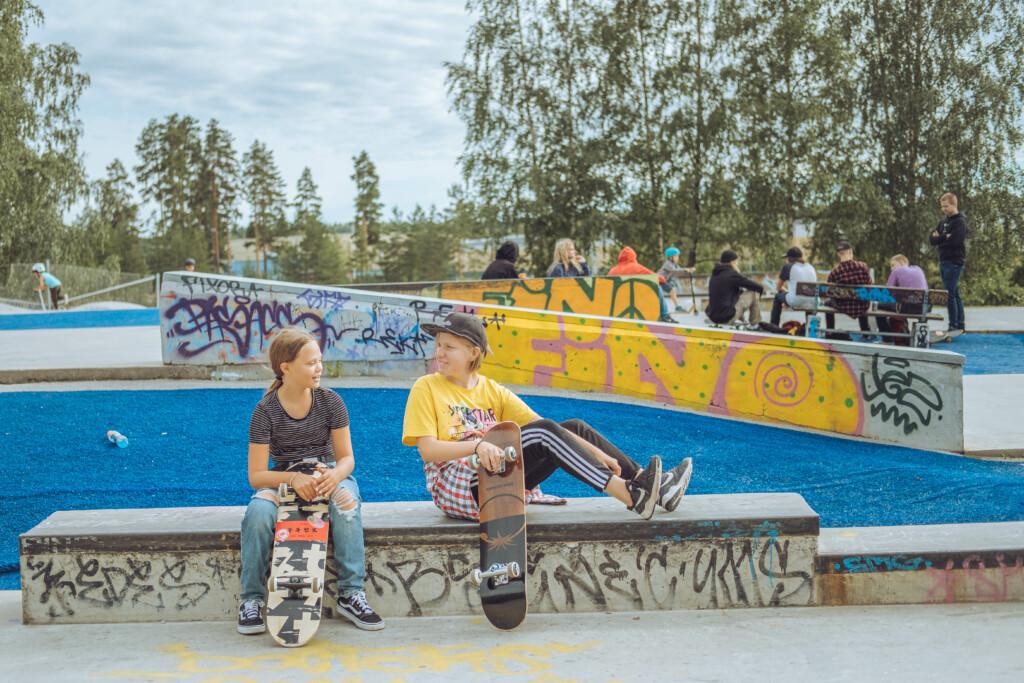 Kaksi nuorta istuu skeittirampilla