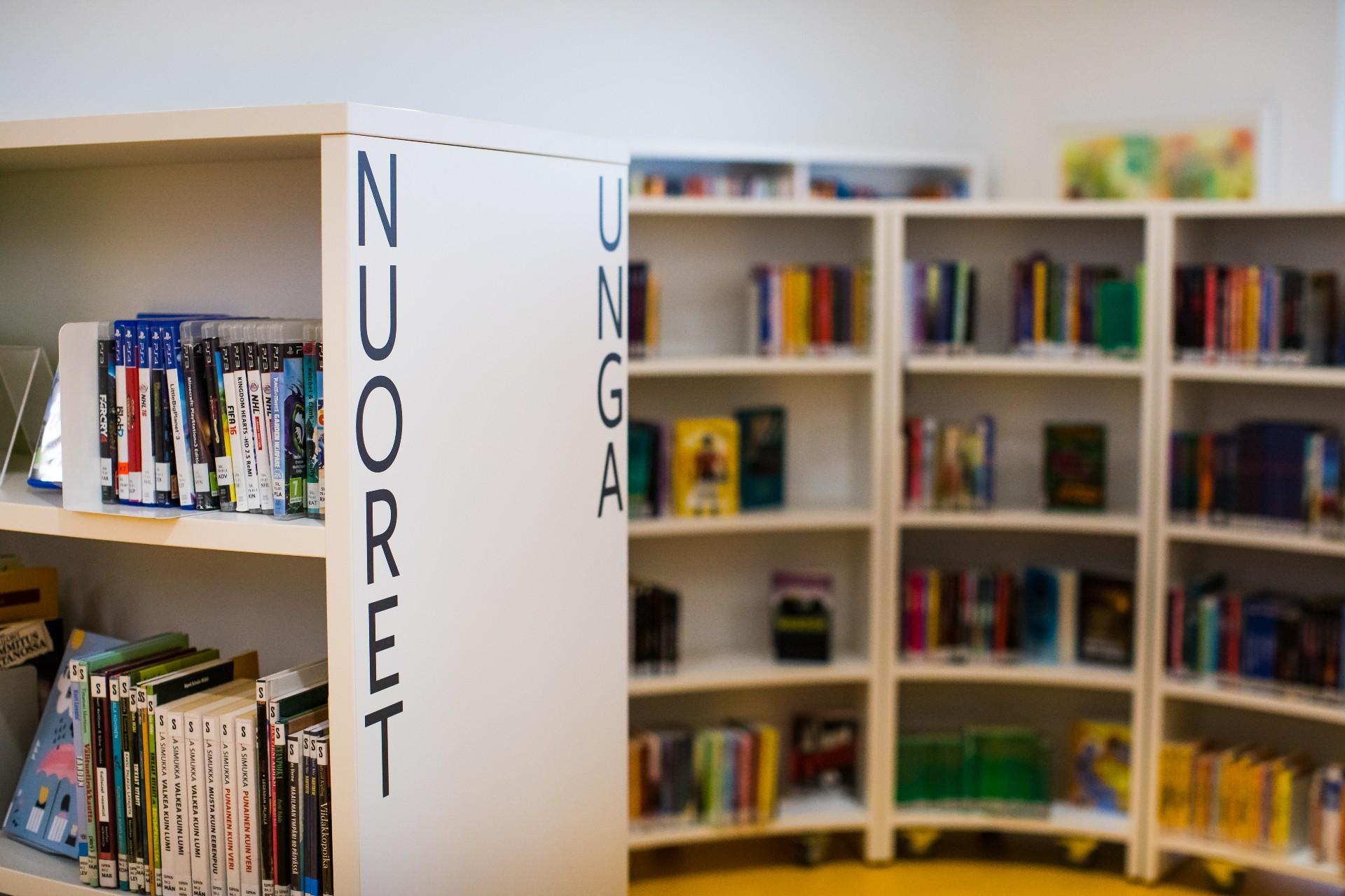 Kirjahyllyjä kirjastossa, joissa lukee teksti nuoret, unga.