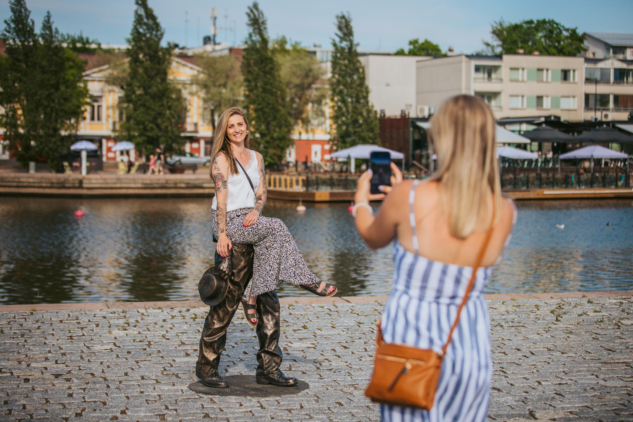 Kaksi henkilöä tutustumassa taiteeseen Porvoon jokirannassa.
